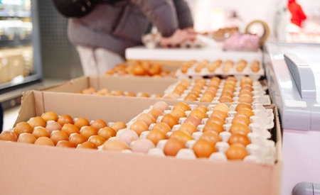 Stacked egg cartons filled with brown eggs on display, showcasing poultry farm produce ready for...