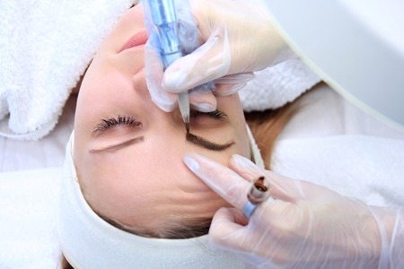 Cosmetologist applying permanent make up on eyebrows eyebrow tattooの写真素材