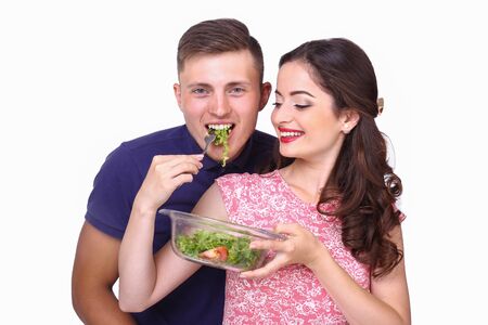 A loving young couple cut vegetables for salad isolated on white background.の写真素材