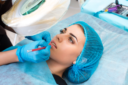 Cosmetologist making permanent makeup on womans faceの写真素材