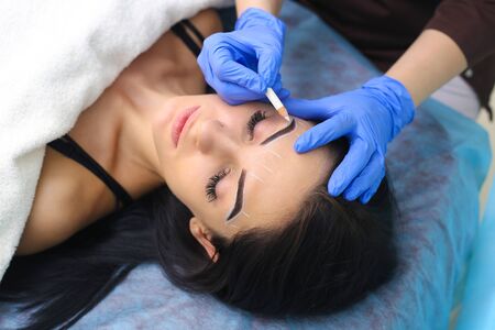 Young beautiful woman making permanent makeup in cosmetology salon.
