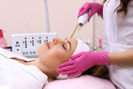 Receiving electric darsonval facial massage procedure.