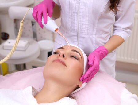 Receiving electric darsonval facial massage procedure.
