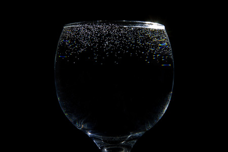 Glass of water with tiny bubbles on black backgroundの写真素材