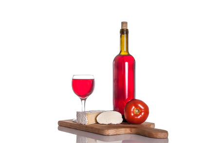 Wine bottle, glass, Brie cheese, mozzarella and tomato on a cutting board.の写真素材