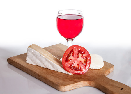Wine glass, Brie cheese, mozzarella and tomato on a cutting board.の写真素材