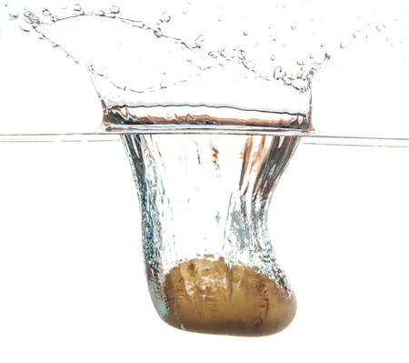 Potato splashing and sinking underwater. White beackgroung.の写真素材