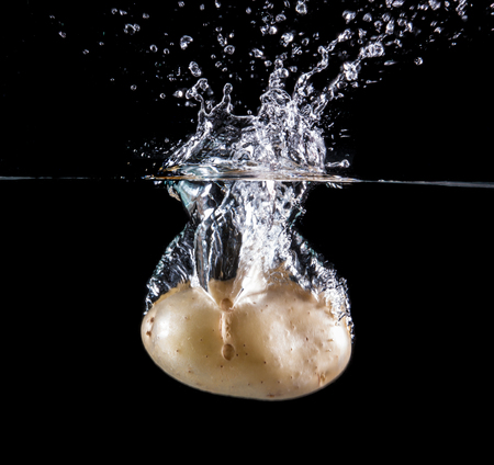 Potato splashing and sinking underwater. White beackgroung.の写真素材