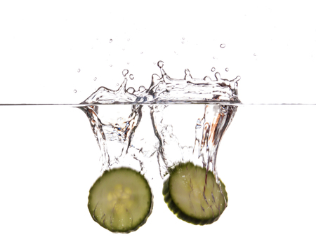 Slice of cucumber sinking underwaterの写真素材