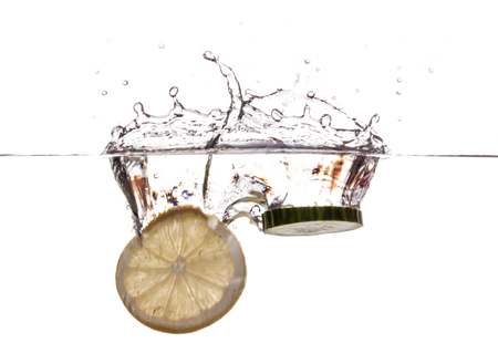 Slice of lemon and cucumber sinking underwaterの写真素材