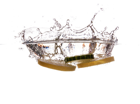 Slice of lemon and cucumber sinking underwaterの写真素材