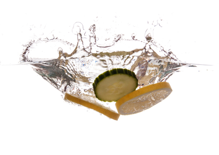 Slice of lemon and cucumber sinking underwaterの写真素材