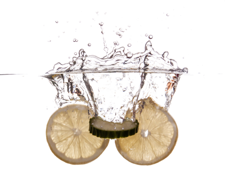 Slice of lemon and cucumber sinking underwaterの写真素材