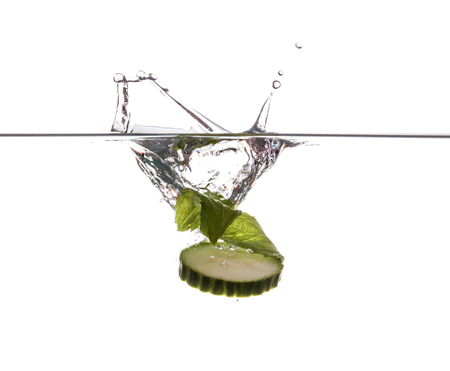 Cucumber slice and mint sinking underwaterの写真素材