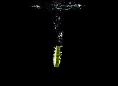 Slice of cucumber sinking underwaterの写真素材