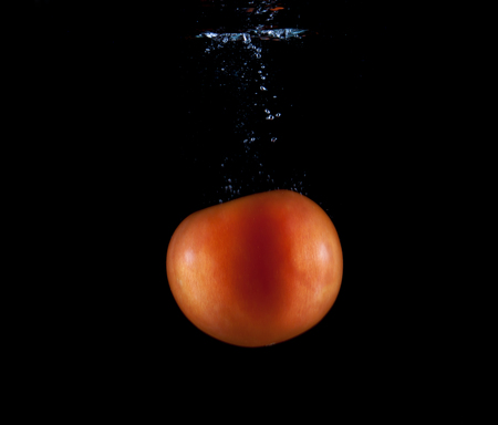 Whole red tomato sinking underwaterの写真素材