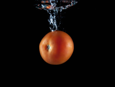 Whole red tomato sinking underwaterの写真素材