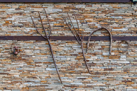 Old agricultural tools hanging on a dry stone wallの写真素材