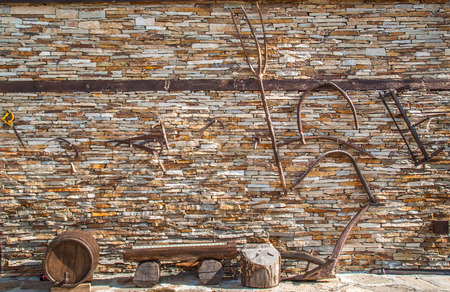 Old agricultural tools hanging on a dry stone wallの写真素材