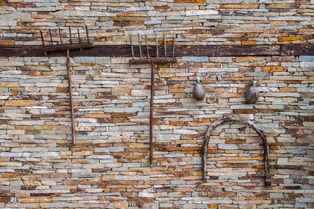 Old agricultural tools hanging on a dry stone wallの写真素材