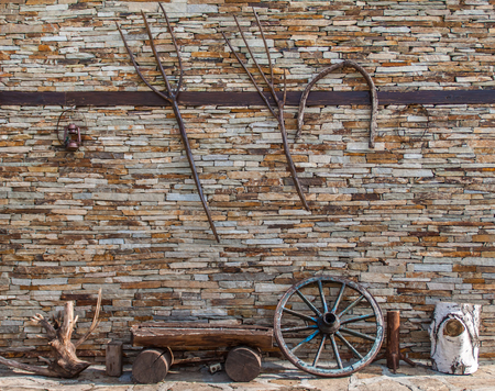 Old agricultural tools hanging on a dry stone wallの写真素材