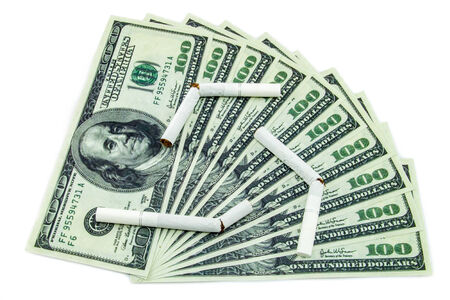 Torn cigarettes lying on a hundred dollar bills arranged as fan and isolated on a white backgroundの写真素材
