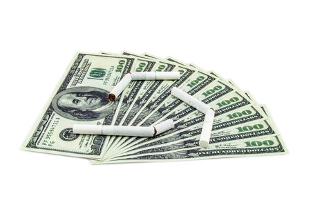 Torn cigarettes lying on a hundred dollar bills arranged as fan and isolated on a white backgroundの写真素材