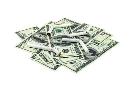 Torn cigarettes lying on a pile of hundred dollar bills isolated on a white backgroundの写真素材