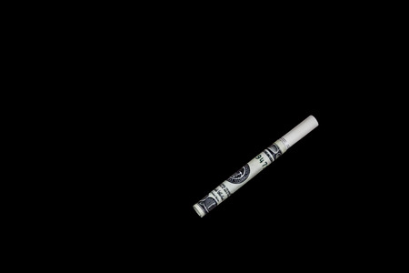 Cigarette made from 100 dollar bills isolated on a black backgroundの写真素材
