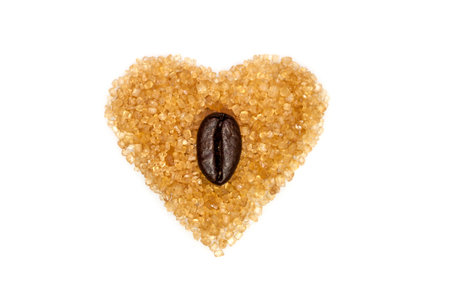 Heart shaped brown sugar with a coffee bean in the center, isolated on whiteの写真素材
