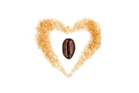 Heart shaped brown sugar with a coffee bean in the center, isolated on whiteの写真素材