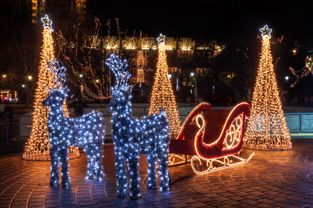Santa Claus sleigh and two reindeer decorated with lightsの写真素材