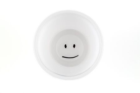White plastic cup with a smiley face on the bottomの写真素材