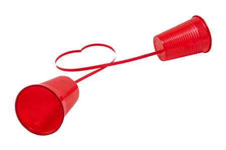 Long distance relationship concept. 2 red plastic cups connected with a red threadの写真素材