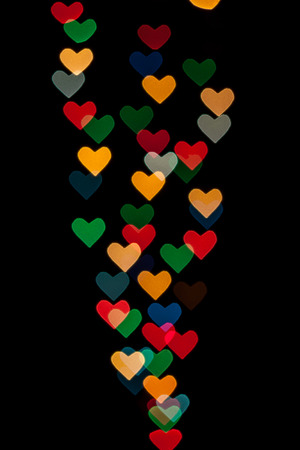 Heart shaped qustom bokeh created from decoration lights and isolated on black background.の写真素材