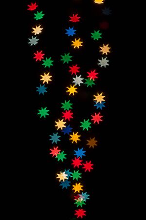 Star shaped qustom bokeh created from decoration lights and isolated on black background.の写真素材