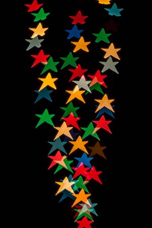 Star shaped qustom bokeh created from decoration lights and isolated on black background.の写真素材