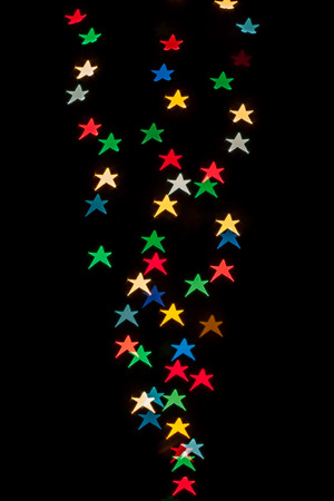 Star shaped qustom bokeh created from decoration lights and isolated on black background.の写真素材