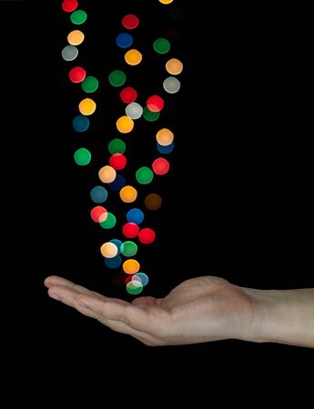 Human hand catching light bokeh bubbles. Isolated on black background.の写真素材