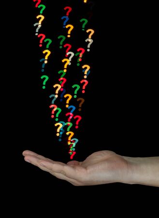 Human hand catching bokeh question marks created from decoration lights. Isolated on black background.の写真素材