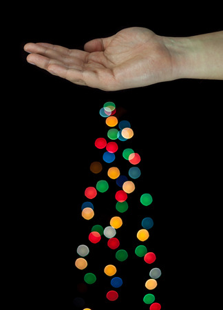 Human hand spreading light bokeh bubbles. Isolated on black background.の写真素材