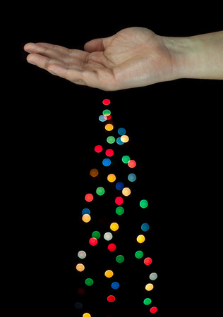 Human hand spreading light bokeh bubbles. Isolated on black background.の写真素材