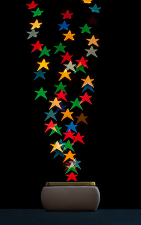 Collecting star shaped bokeh lights in a box. Isolated on black background.の写真素材