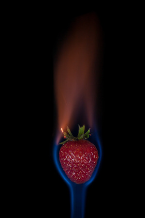 Strawberry on fire with blue flames isolated on black backgroundの写真素材