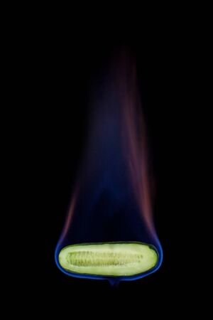 Cucumber on fire with blue flames isolated on black background