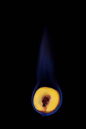 Peach on fire with blue flames isolated on black backgroundの写真素材