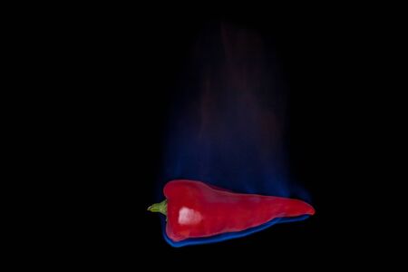 Red Pepper on fire with blue flames isolated on black backgroundの写真素材