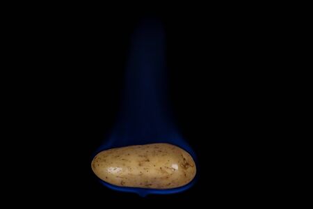 Potato on fire with blue flames isolated on black backgroundのeditorial素材