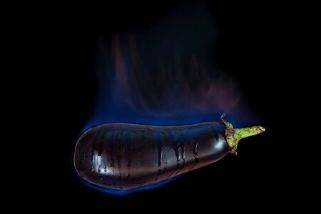 Eggplant on fire with blue flames isolated on black backgroundの写真素材
