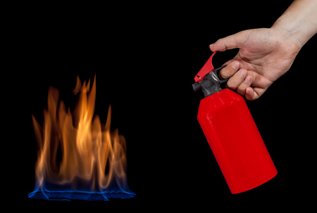 Human hand holding fire extinguisher and a blue flame isolated on black backgroundの写真素材